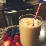 A vibrant kefir smoothie poured into a mason jar, garnished with mint leaves, surrounded by fresh fruits.